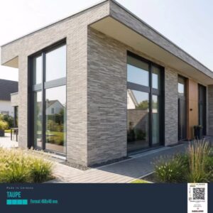 Contemporary single-story house with large glass windows, dark frames, and gray stone veneer exterior, plus a manicured front path and plants.