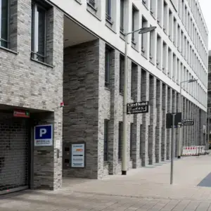 Modern brick-and-plaster building with many windows and street lamps along an empty sidewalk.