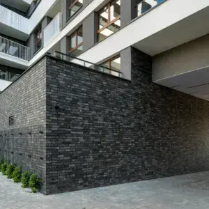 Modern building exterior with dark brick base, white balcony levels, and large windows.