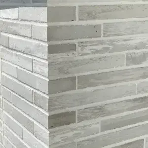 Exterior corner of a building with light gray brick walls meeting at a right angle.